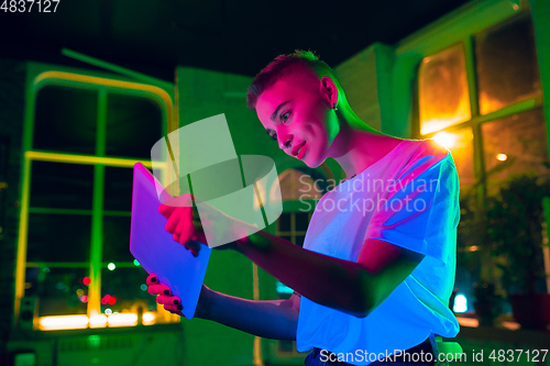 Image of Cinematic portrait of handsome young woman in neon lighted interior