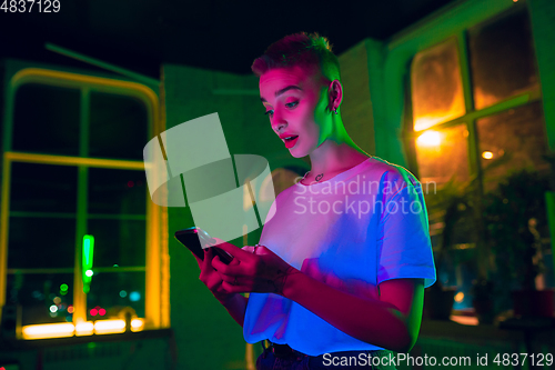 Image of Cinematic portrait of handsome young woman in neon lighted interior