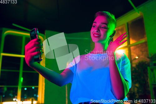 Image of Cinematic portrait of handsome young woman in neon lighted interior