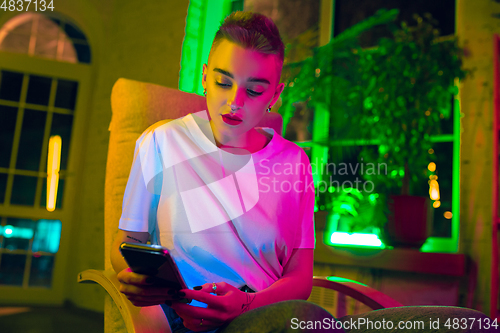 Image of Cinematic portrait of handsome young woman in neon lighted interior