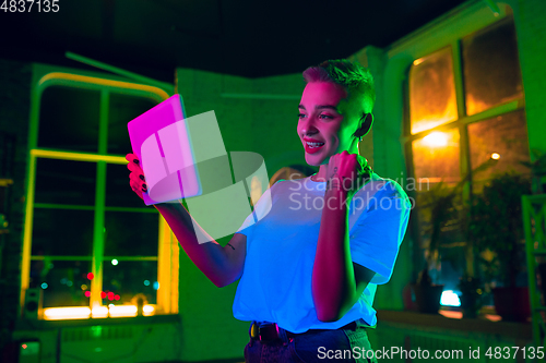 Image of Cinematic portrait of handsome young woman in neon lighted interior