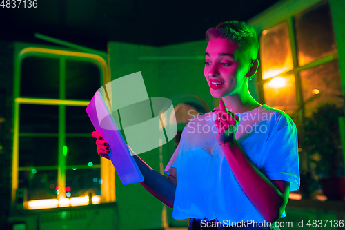 Image of Cinematic portrait of handsome young woman in neon lighted interior