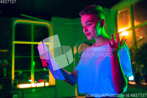 Image of Cinematic portrait of handsome young woman in neon lighted interior