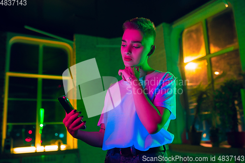 Image of Cinematic portrait of handsome young woman in neon lighted interior