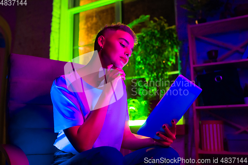 Image of Cinematic portrait of handsome young woman in neon lighted interior