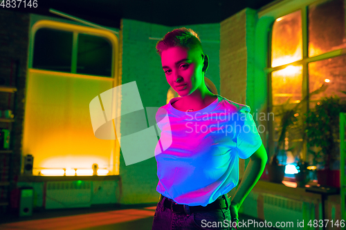 Image of Cinematic portrait of handsome young woman in neon lighted interior