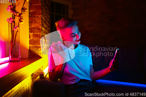 Image of Cinematic portrait of handsome young woman in neon lighted interior