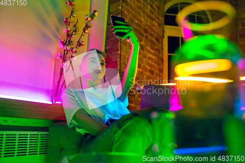 Image of Cinematic portrait of handsome young woman in neon lighted interior