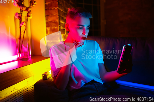 Image of Cinematic portrait of handsome young woman in neon lighted interior