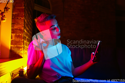 Image of Cinematic portrait of handsome young woman in neon lighted interior