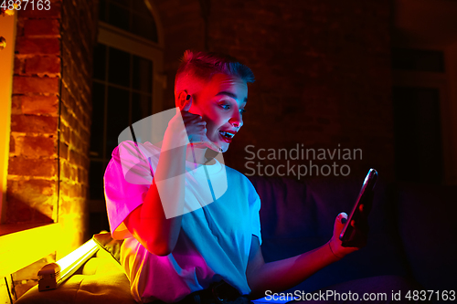 Image of Cinematic portrait of handsome young woman in neon lighted interior