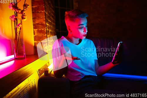 Image of Cinematic portrait of handsome young woman in neon lighted interior