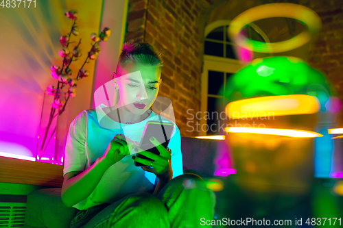 Image of Cinematic portrait of handsome young woman in neon lighted interior