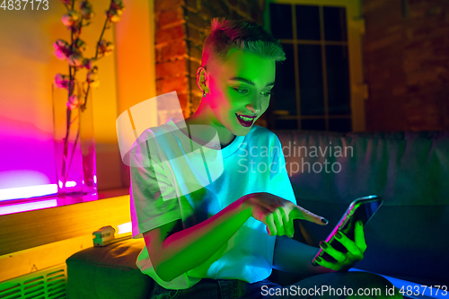 Image of Cinematic portrait of handsome young woman in neon lighted interior