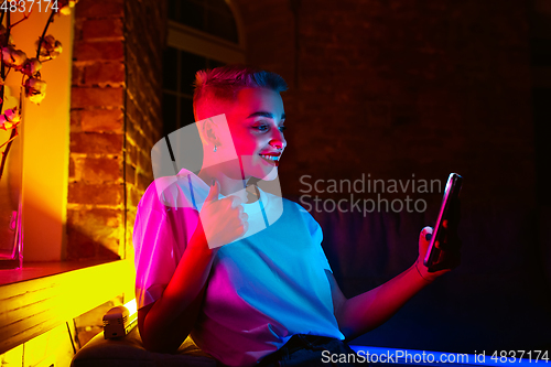 Image of Cinematic portrait of handsome young woman in neon lighted interior