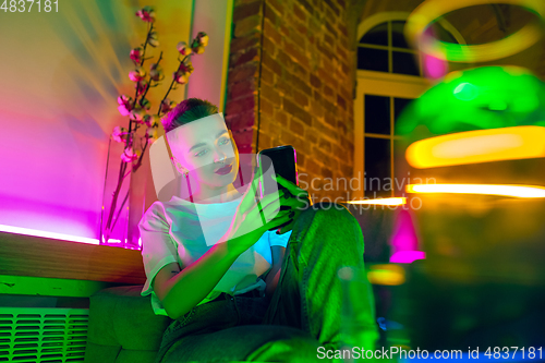 Image of Cinematic portrait of handsome young woman in neon lighted interior