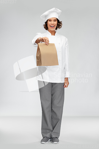 Image of happy female chef with takeaway food in paper bag