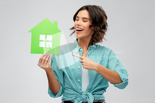 Image of smiling young woman showing green house