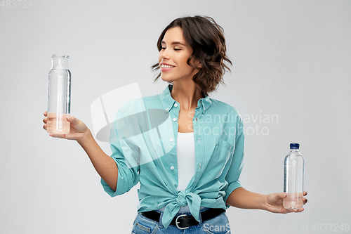 Image of smiling young woman comparing bottles of water