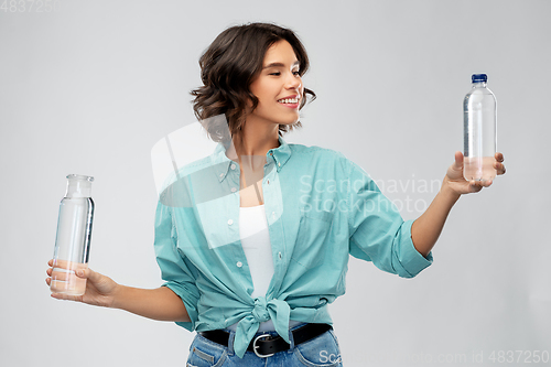 Image of smiling young woman comparing bottles of water