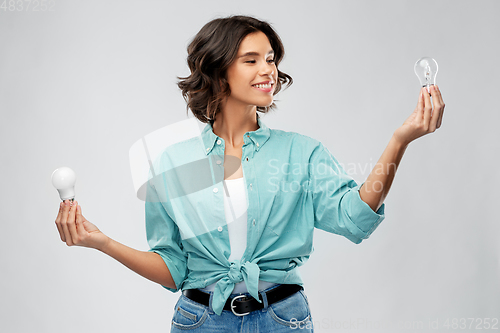 Image of smiling woman comparing different light bulbs