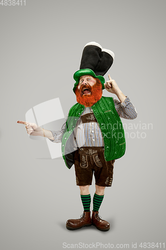 Image of Excited leprechaun in green suit with red beard on white background
