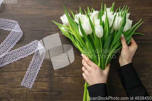 Image of Florist at work: woman making fashion modern bouquet of different flowers on wooden background