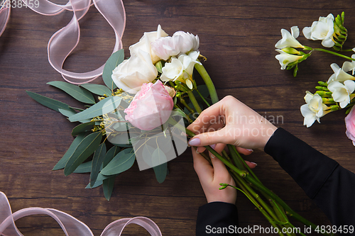 Image of Florist at work: woman making fashion modern bouquet of different flowers on wooden background