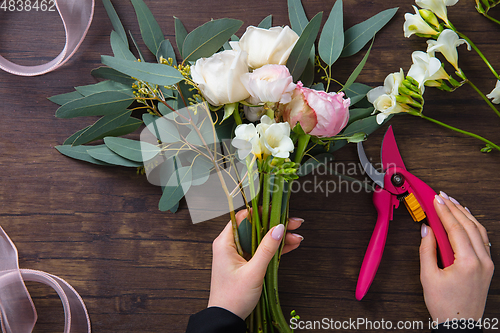 Image of Florist at work: woman making fashion modern bouquet of different flowers on wooden background