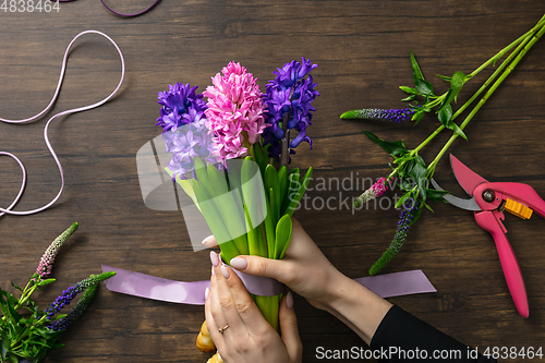 Image of Florist at work: woman making fashion modern bouquet of different flowers on wooden background