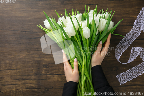 Image of Florist at work: woman making fashion modern bouquet of different flowers on wooden background