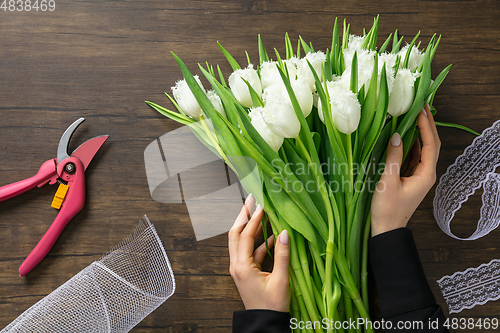 Image of Florist at work: woman making fashion modern bouquet of different flowers on wooden background