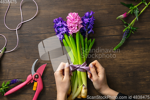 Image of Florist at work: woman making fashion modern bouquet of different flowers on wooden background