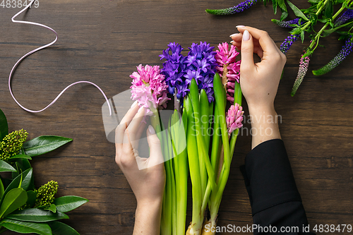 Image of Florist at work: woman making fashion modern bouquet of different flowers on wooden background