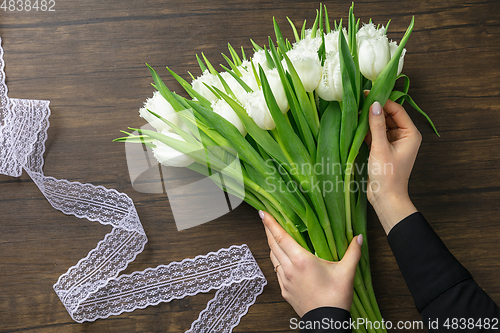 Image of Florist at work: woman making fashion modern bouquet of different flowers on wooden background