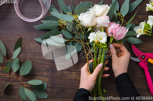 Image of Florist at work: woman making fashion modern bouquet of different flowers on wooden background