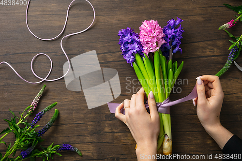 Image of Florist at work: woman making fashion modern bouquet of different flowers on wooden background