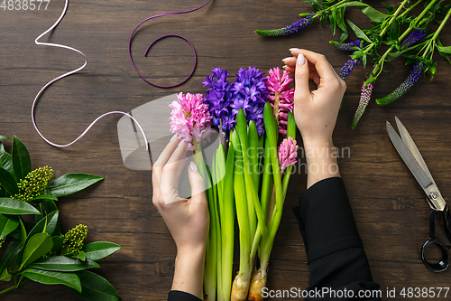 Image of Florist at work: woman making fashion modern bouquet of different flowers on wooden background