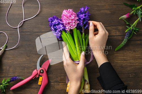 Image of Florist at work: woman making fashion modern bouquet of different flowers on wooden background