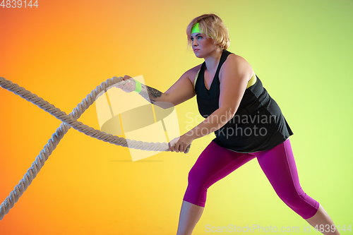 Image of Young caucasian plus size female model\'s training on gradient orange background