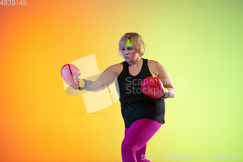 Image of Young caucasian plus size female model\'s training on gradient orange background