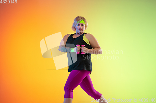 Image of Young caucasian plus size female model\'s training on gradient orange background