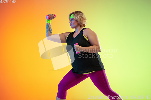 Image of Young caucasian plus size female model\'s training on gradient orange background