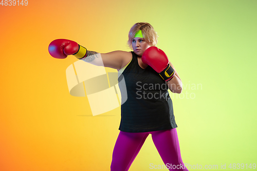 Image of Young caucasian plus size female model\'s training on gradient orange background