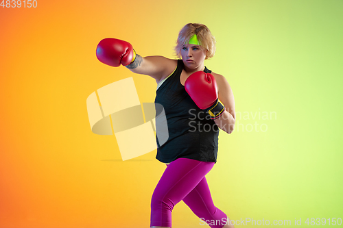 Image of Young caucasian plus size female model\'s training on gradient orange background