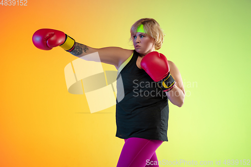 Image of Young caucasian plus size female model\'s training on gradient orange background