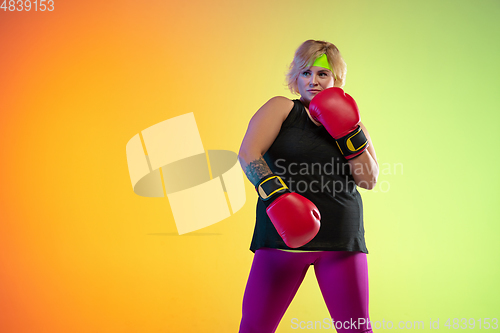 Image of Young caucasian plus size female model\'s training on gradient orange background
