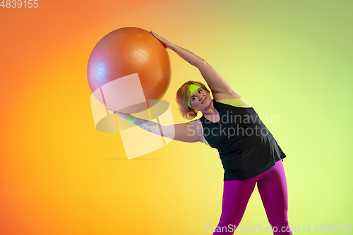 Image of Young caucasian plus size female model\'s training on gradient orange background