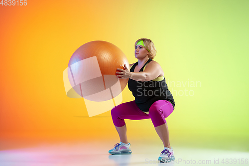 Image of Young caucasian plus size female model\'s training on gradient orange background