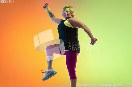 Image of Young caucasian plus size female model\'s training on gradient orange background